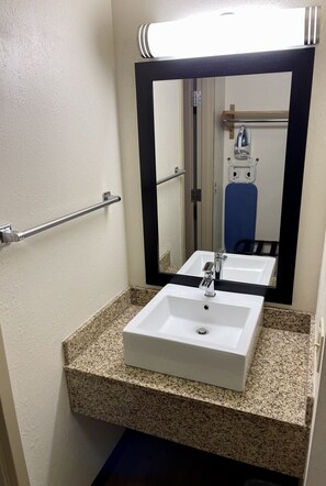 A bathroom with a white sink, granite countertop, and a mirror with a black frame. - Red Roof Inn Sandusky - Milan (Milan)