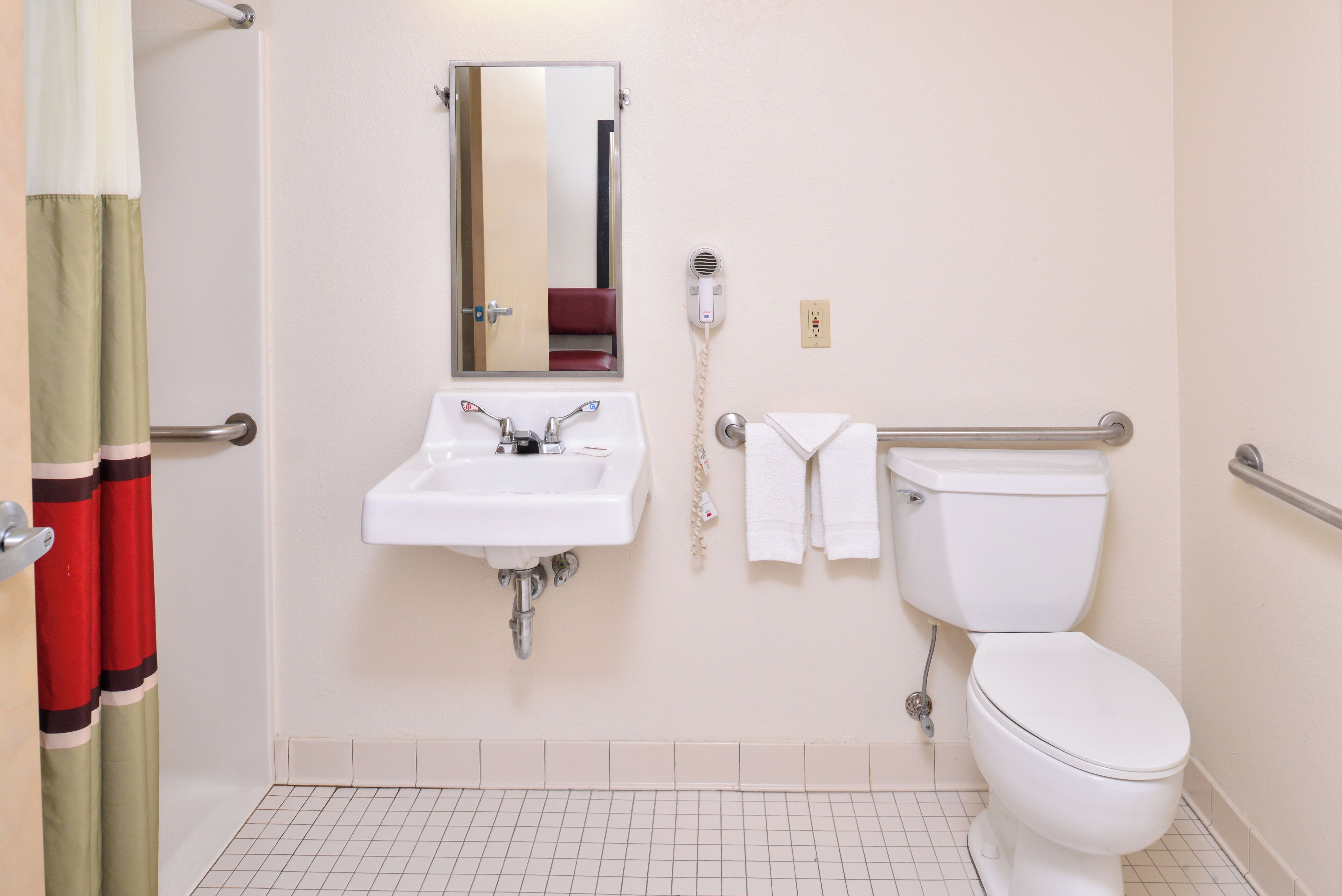 A bathroom with a sink, mirror, toilet, and towel rack.