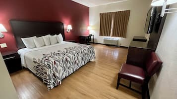 Habitación de hotel con cama, mesitas de noche, escritorio, silla, televisión y ventana con cortinas.