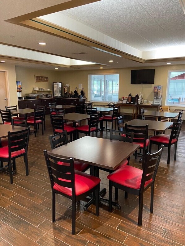 A restaurant with multiple tables and chairs, a counter with a beverage dispenser, and a television mounted on the wall. - Red Roof Inn Sandusky - Milan (Milan)
