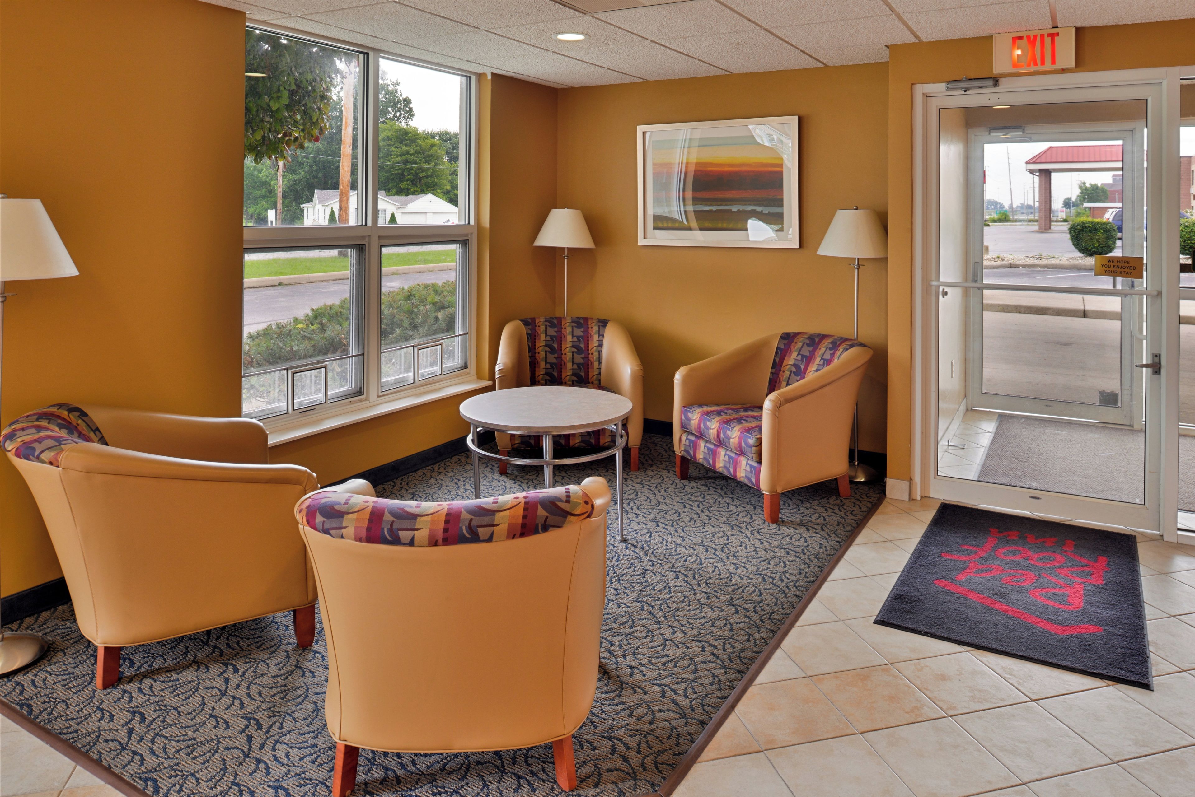 A hotel lobby with two armchairs, a small round table, and a painting on the wall.