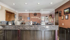 A reception area with a marble counter, a clock, and a sign that reads "RODEWAY." - Rodeway Inn Old Town Temecula (Temecula)