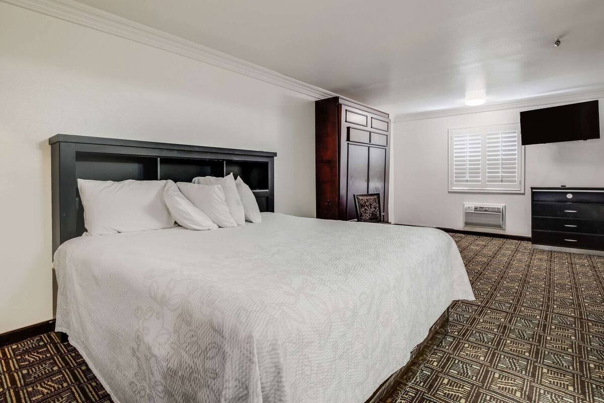 A hotel room with a large bed, a wardrobe, a desk, and a television.