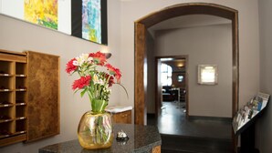 Un couloir avec un vase de fleurs posé sur un comptoir, un porte-revues en bois et un escalier.