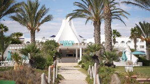 A white building with a sign reading "SNACK BAR" in front.
