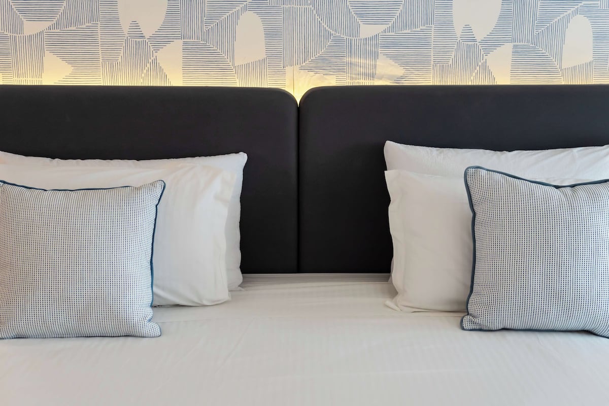 A hotel room with a bed featuring two pillows with a dotted pattern and a dark headboard.