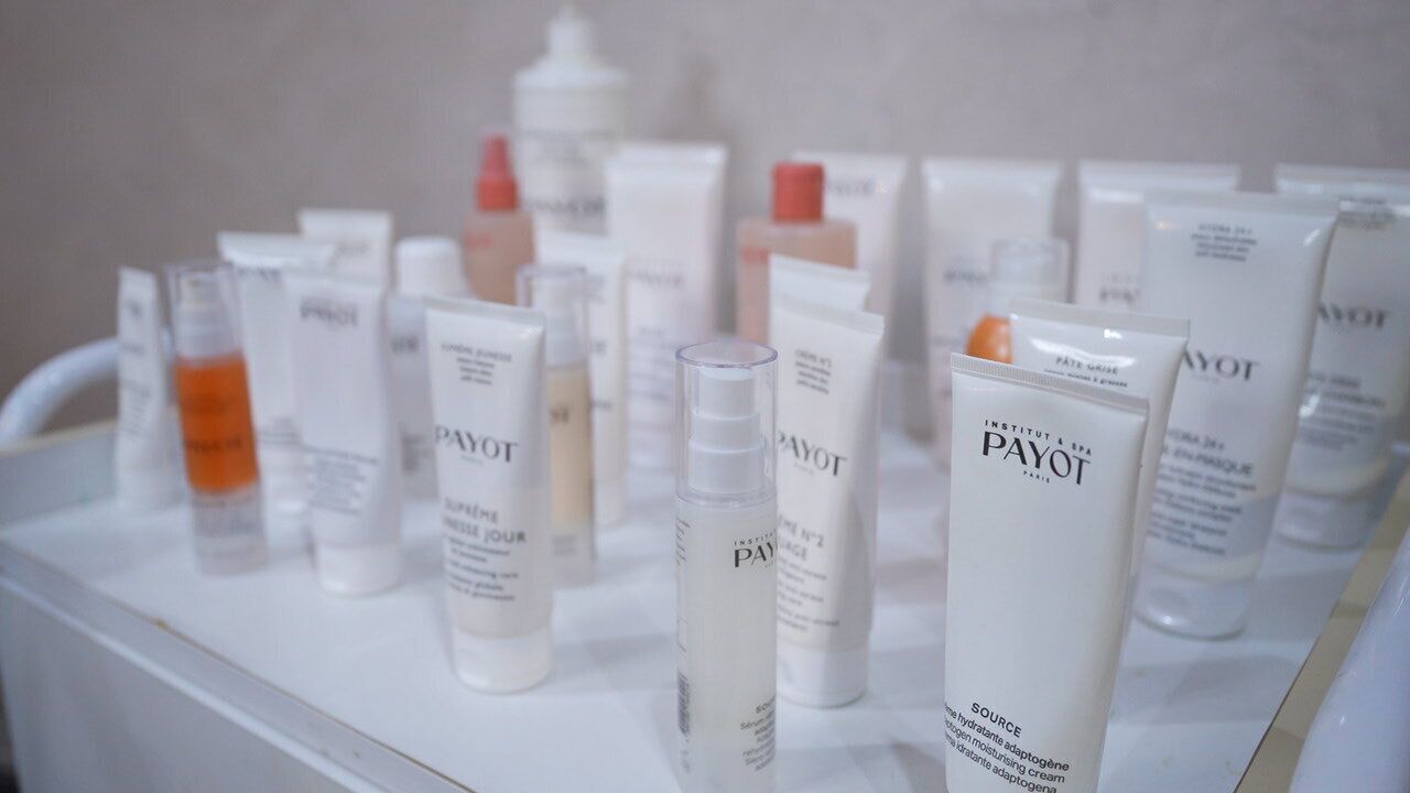 A display of various skincare products on a white shelf.