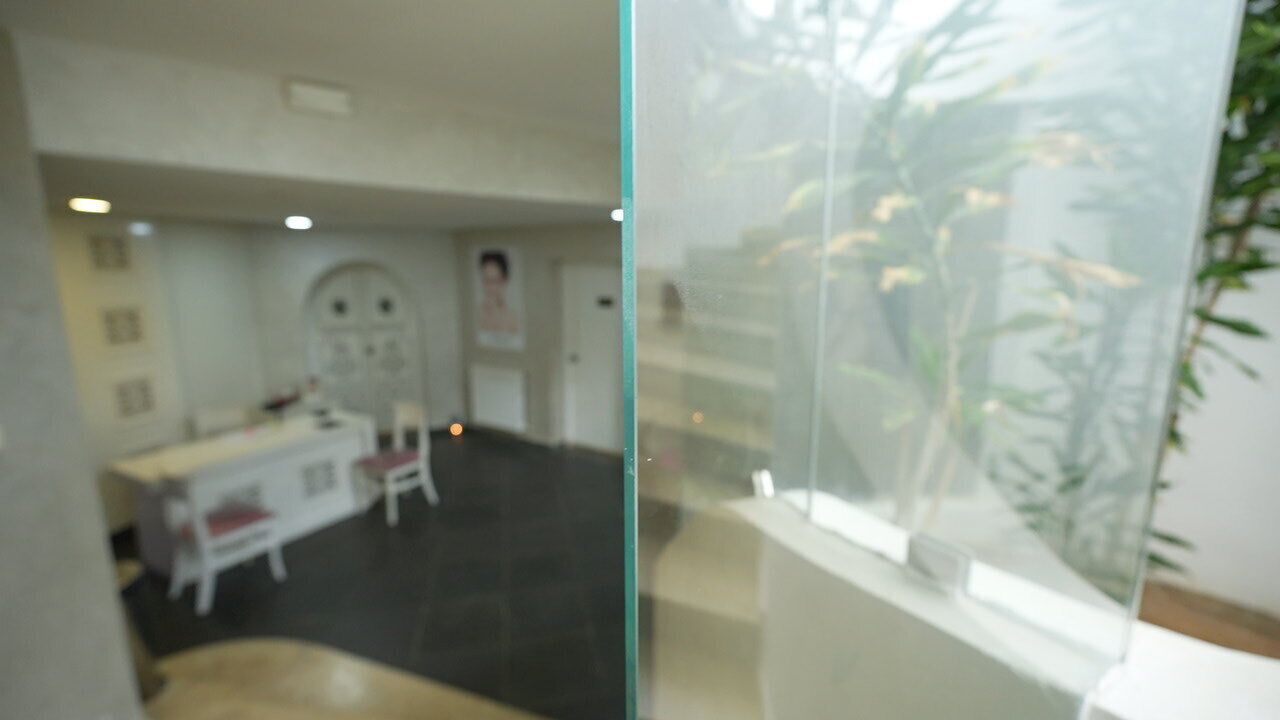Ein Zimmer mit Glastrennwand, Schreibtisch, Stühlen und einer Pflanze.