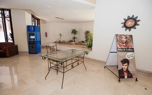 A lobby with a glass-top table, a blue ATM, and a salon sign. - El Kantaoui Center and Spa (Port El Kantaoui)