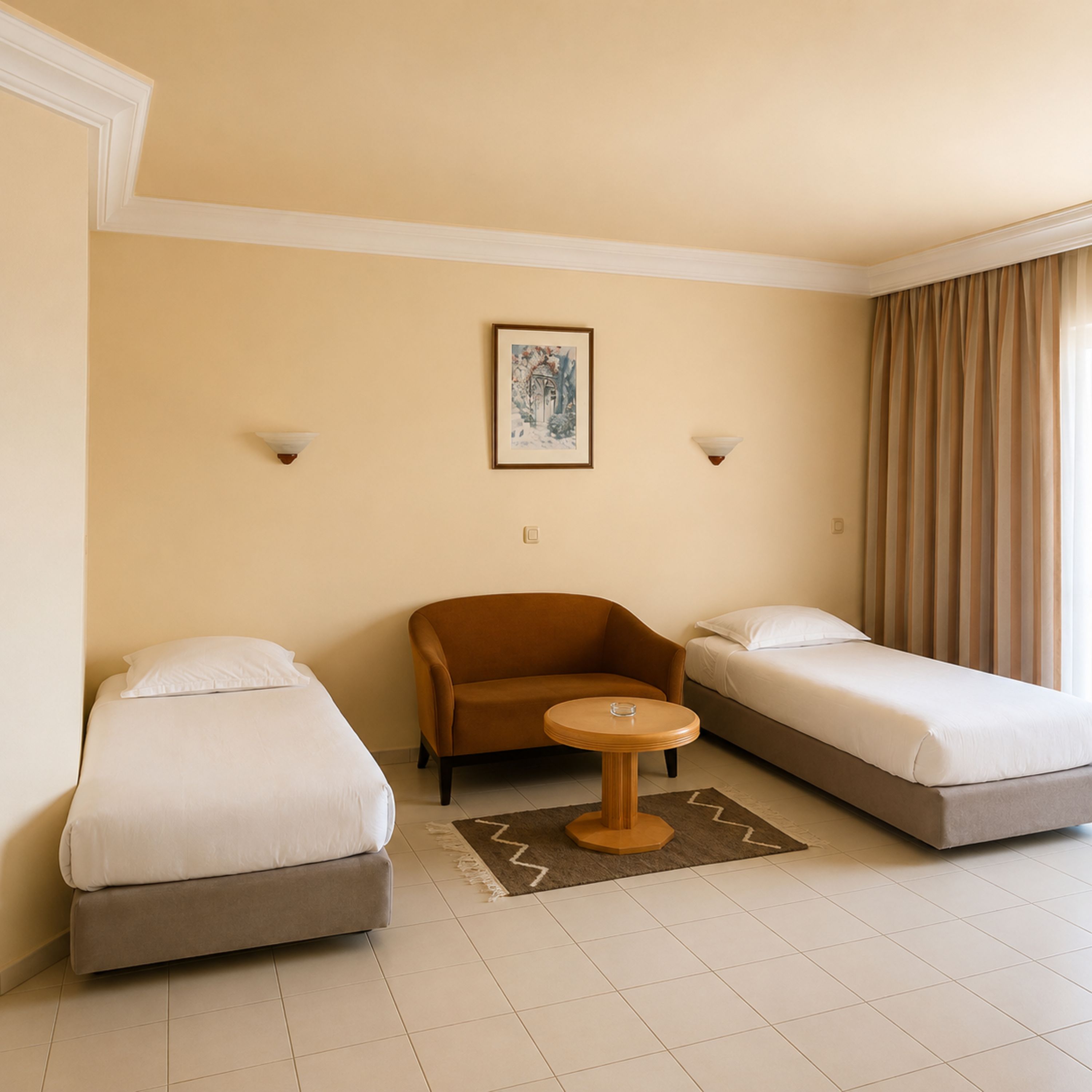 Habitación de hotel con dos camas individuales, una mesa redonda pequeña y un sofá.