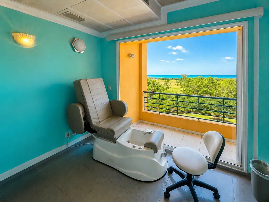 Une pièce équipée d’un fauteuil de massage, d’une petite table et offrant une vue sur l’océan depuis un balcon.