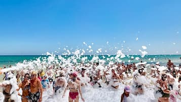 Escena de playa con gente cubierta de espuma.