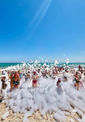 Une scène de plage où l’on voit des personnes couvertes d’écume.