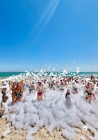 Escena de playa con gente cubierta de espuma.