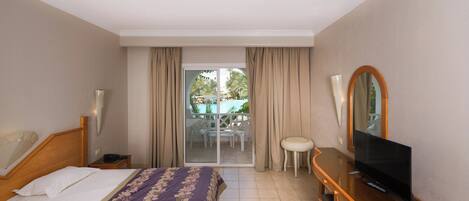 Une chambre d’hôtel avec un lit, une télévision, un bureau et un balcon donnant sur la piscine.
