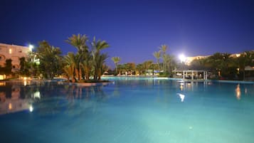Una piscina techada, una piscina al aire libre, sombrillas