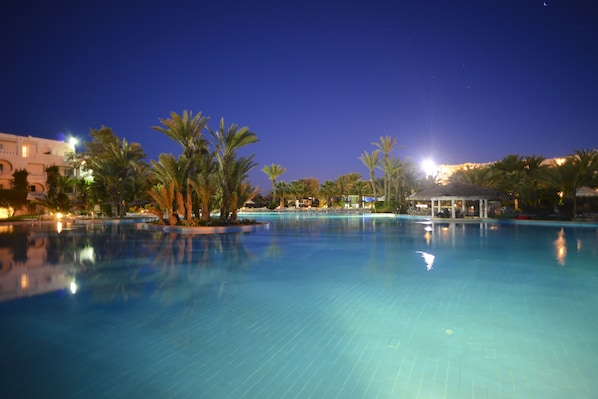 Una piscina cubierta, una piscina al aire libre, sombrillas, tumbonas