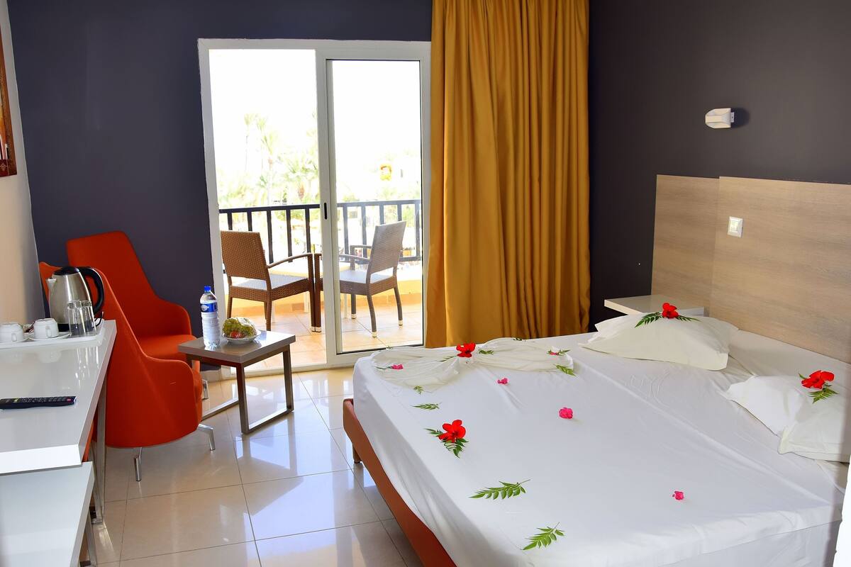 A hotel room with a bed, a desk, a chair, and a balcony.