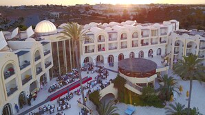 A hotel with multiple floors, outdoor dining areas, and a central courtyard with a fountain. - Eden Star Resort (Zarzis)