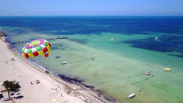 En la playa, sillas reclinables de playa, sombrillas, ski acuático