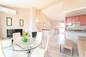 A modern kitchen with a microwave, stove, and cabinets. There is a dining area with a glass table and chairs.