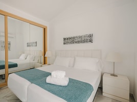 Una habitación de hotel con una cama grande, dos mesitas de noche, un espejo y obras de arte en la pared.