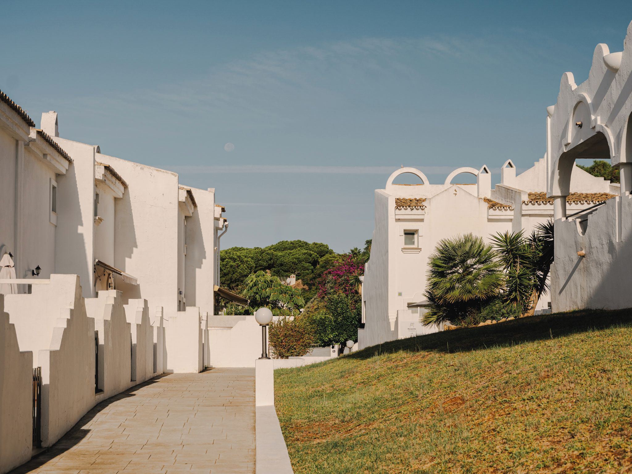A pathway leading to a white building with a sloped roof and a small window.
