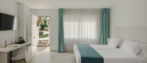A hotel room with a bed, a desk, a chair, a TV, and a window with curtains.