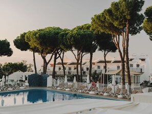 Ein Poolbereich mit Liegestühlen, einem Schwimmbecken und einer Reihe von Gebäuden mit Balkonen.