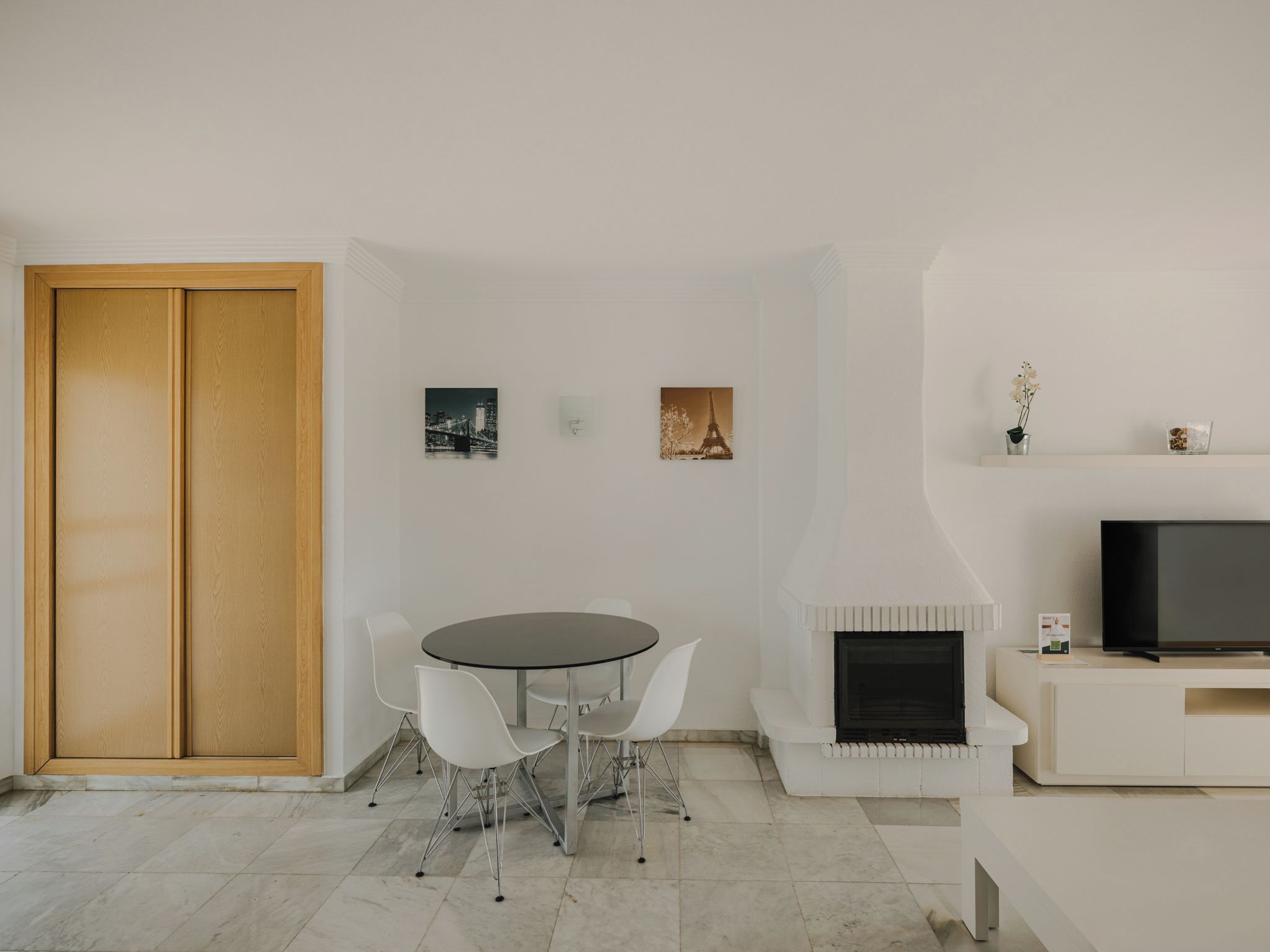 Una sala de estar moderna con comedor, televisor y obras de arte en la pared.