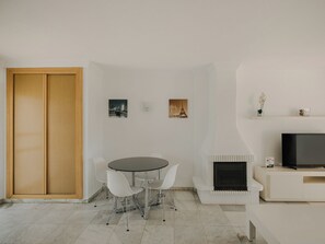 Ein modernes Wohnzimmer mit Essbereich, Fernseher und Kunstwerken an der Wand.