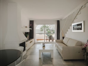 Un salon moderne avec un canapé, une table basse, un téléviseur et un escalier.
