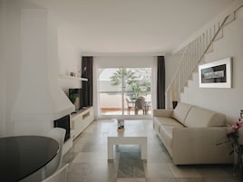 Una sala de estar moderna con un sofá, una mesa de centro, un televisor y una escalera.