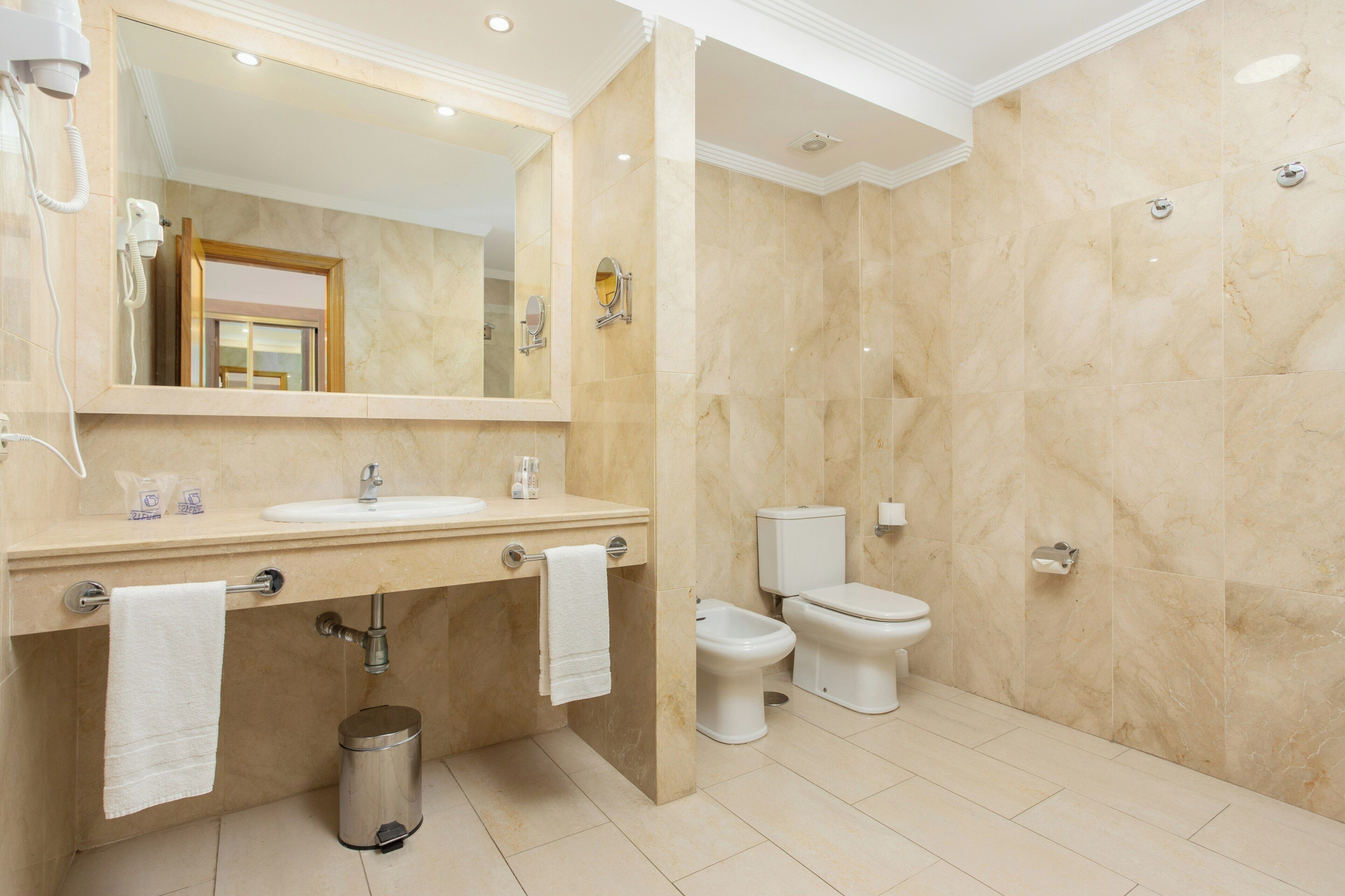 Een badkamer met een wastafel, spiegel, toilet en douche.