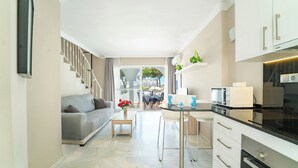 Een moderne keuken met een zithoek, een grijze bank en een trap naar een buitenruimte.