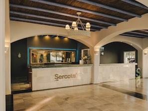Un hall d’accueil d’hôtel avec un comptoir en marbre, un lustre et un design moderne.