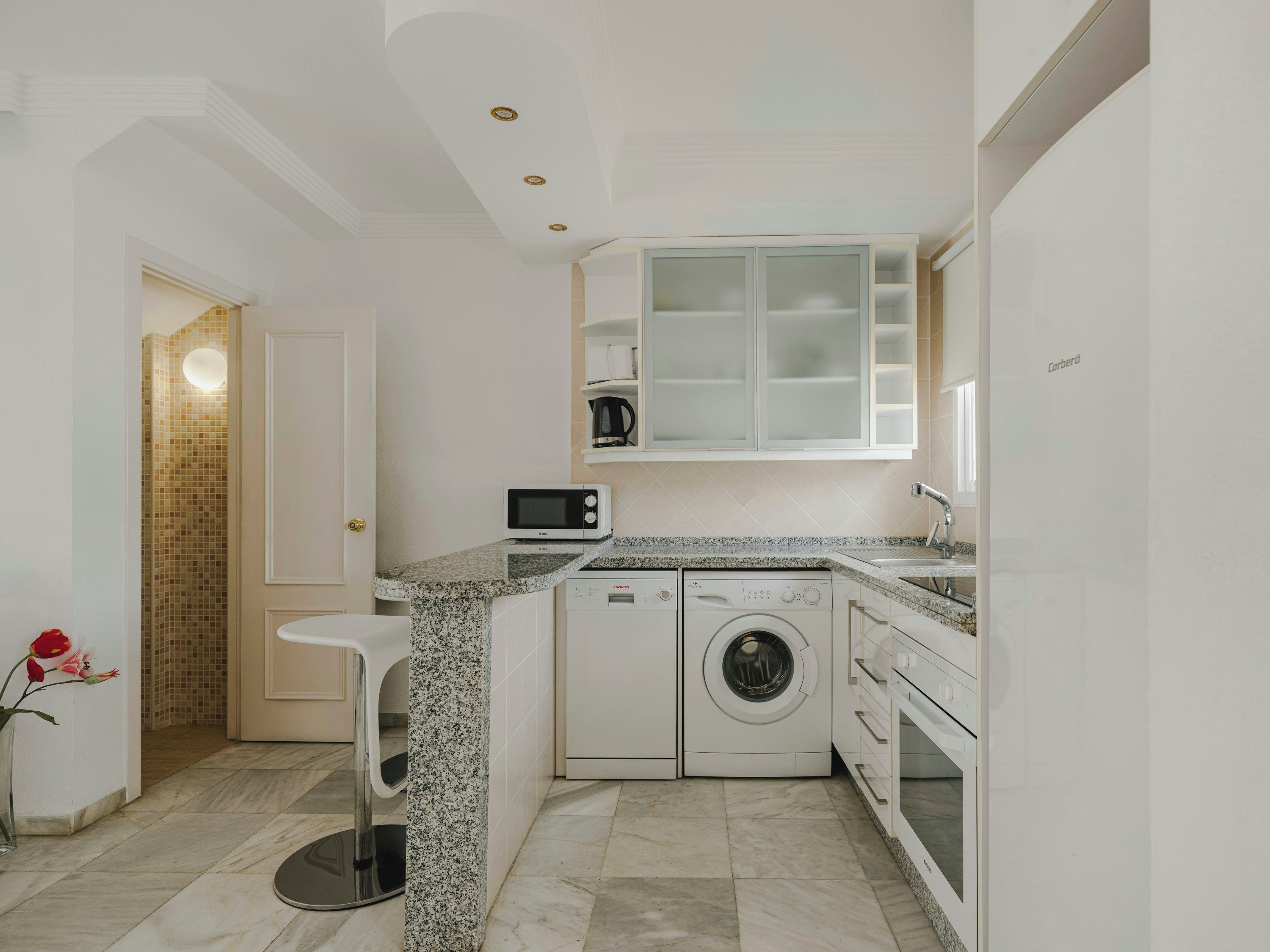 Una cocina moderna con encimera de granito, electrodomésticos integrados y lavadora.
