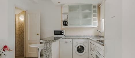 Una cocina moderna con lavadora integrada, microondas y pileta.