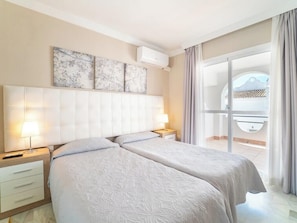 Una habitación de hotel con dos camas, un ventanal grande y un balcón.