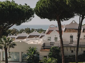 Ein Küstenhotel mit mehreren weißen Gebäuden, Blick auf das Meer und üppigem Grün.