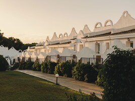 Una hilera de edificios blancos con ventanas arqueadas y un camino que lleva a la entrada.