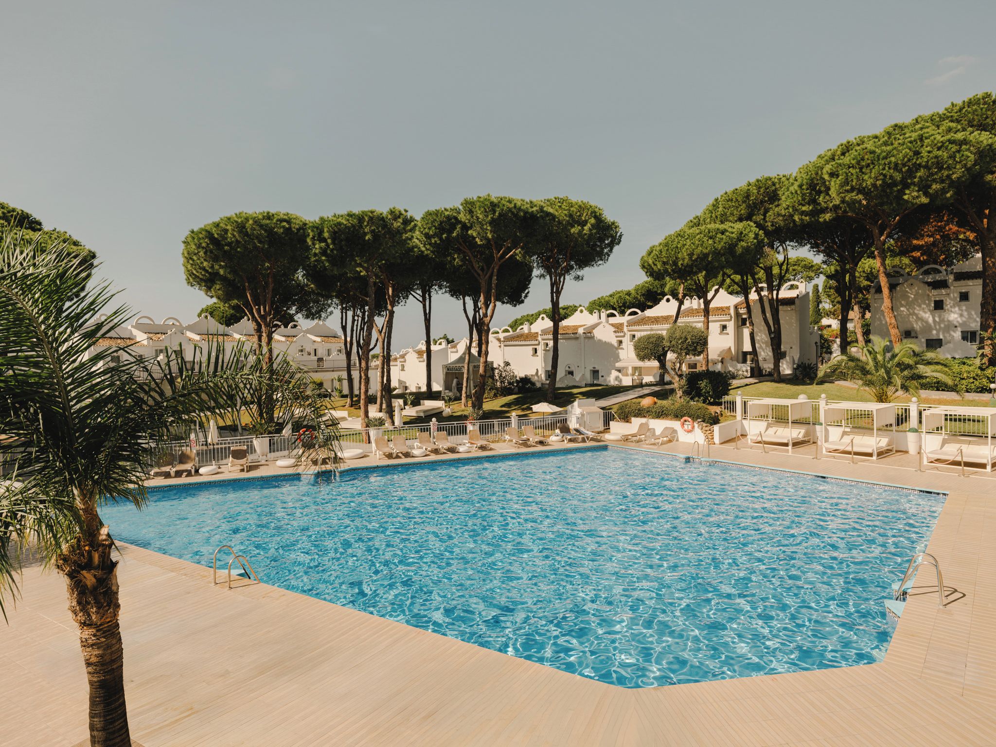 Una piscina con lettini e un cartello per massaggi.