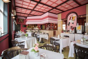 Experience the unique architectural design and warm atmosphere of this restaurant, featuring a geometric ceiling, wooden furniture, and a vibrant mural.