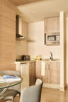A modern kitchen with a microwave, sink, and a dining area with a glass table and chairs.