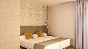 A modern hotel room with a large bed, a headboard with a textured wall, a hanging light fixture, and a view of the outside through a window with curtains.
