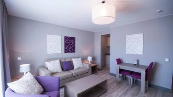A modern living room with a sofa, a dining table, and chairs, a coffee table, and artwork on the walls.