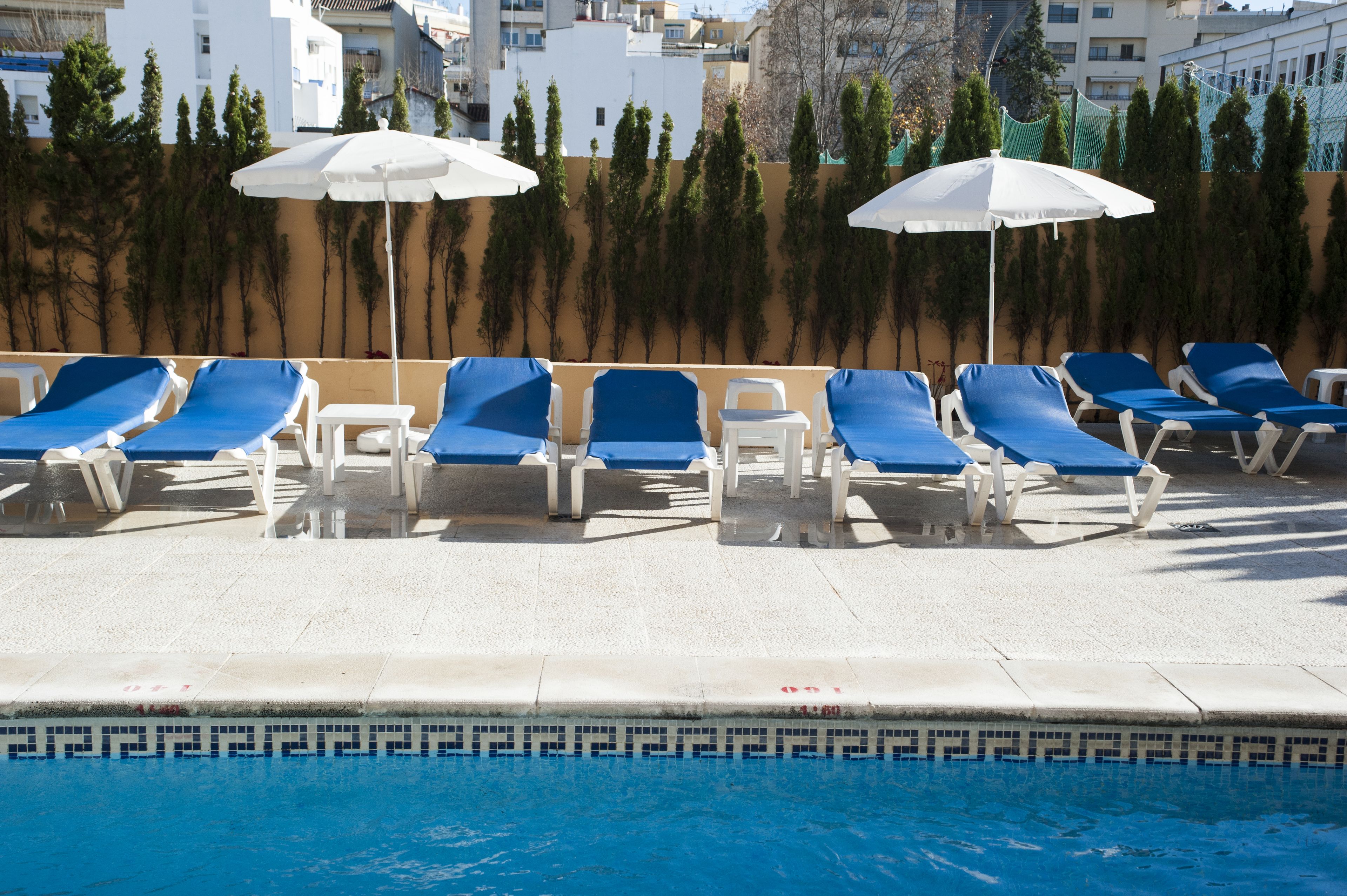 A poolside area with blue lounge chairs and white umbrellas.