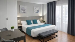 A modern hotel room with a large bed, a bedside table, a desk with a chair, and a window with curtains. - Hotel El Faro Marbella (Marbella)
