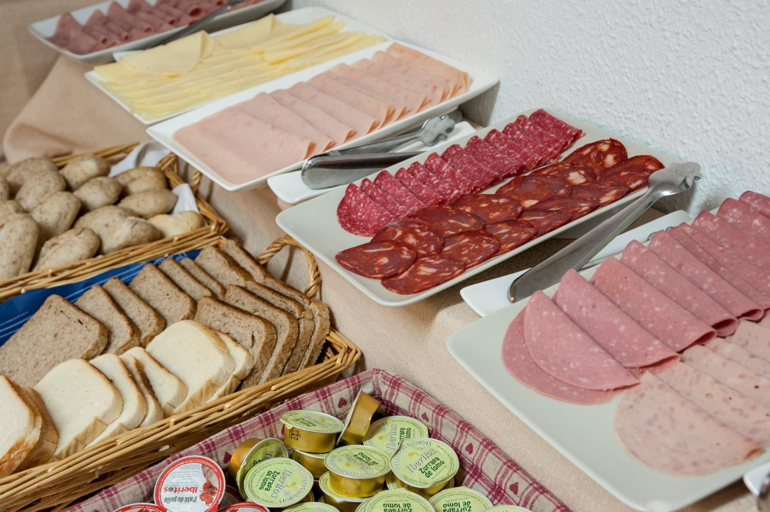 A variety of food items including sliced meats, cheeses, and bread, arranged on a table.