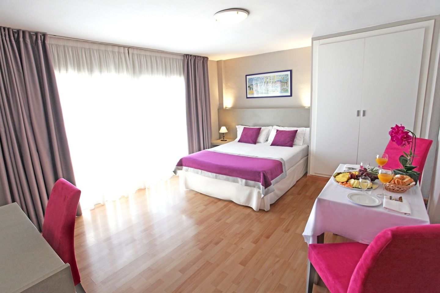 Une chambre d’hôtel avec un lit, un bureau où le petit-déjeuner est servi, et une vue sur l’extérieur.